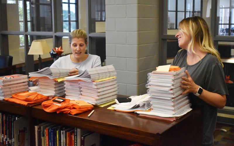 Habersham Central teachers Kelli Holland and Dr. Kathleen Addison pick up their first day packets and shirts in the media center Monday afternoon. School starts for students Friday. MATTHEW OSBORNE/Staff