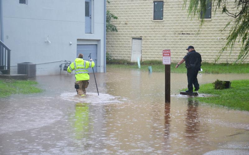 Cornelia first responders wade through a flooded parking lot outside of  Structure Hair Studio in Cornelia on Tuesday afternoon. BRIAN WELLMEIER/Staff