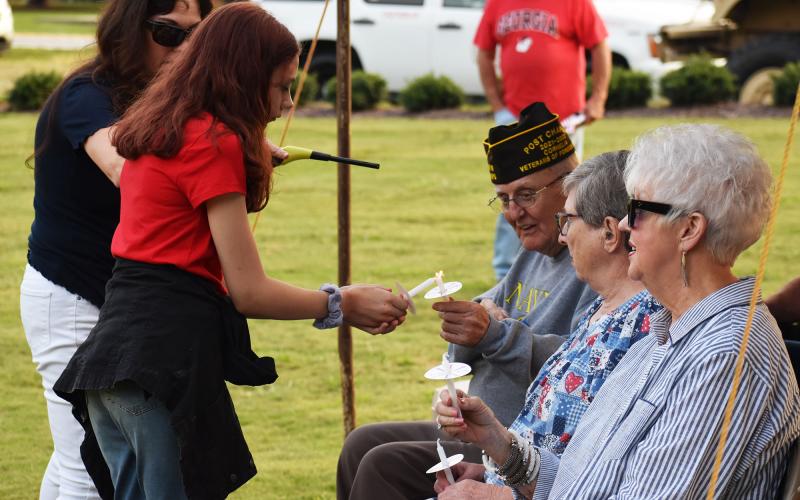 Baylee Morgan lights a candle with VFW Chaplain Fred White during a memorial event Saturday night in Cornelia. MATTHEW OSBORNE/Staff