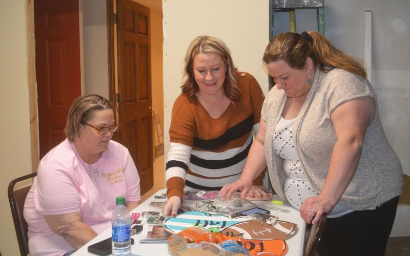 April Clark, Ashley York and Carrie Watts sort items available in the silent auction for Clark. BRIAN WELLMEIER/Staff