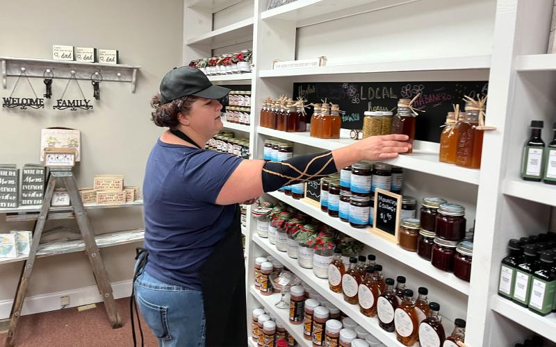 Mandy Hicks organizes her wall of Amish-made jellies and other delights at Mountainside Exchange in Clarkesville. MATTHEW OSBORNE/Staff