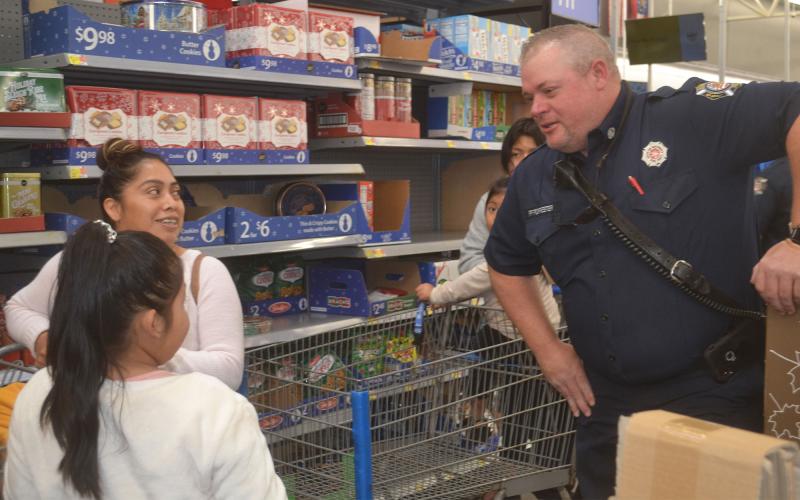 Firefighter Tim Forrester interacts with a young girl and her mother as they shop for toys. BRIAN WELLMEIER/Staff