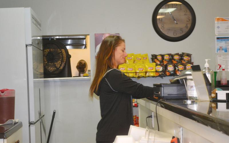 Michelle Smith works behind the counter at Side Street Deli in Cornelia. BRIAN WELLMEIER/Staff