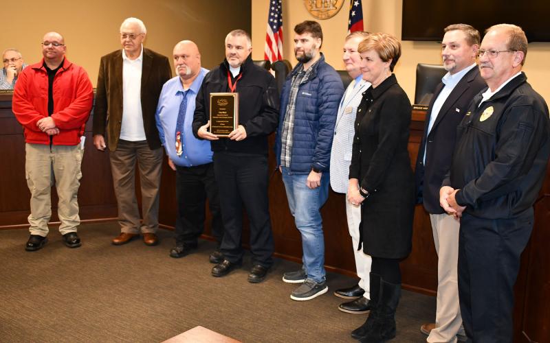 Chad Black (center with plaque) was recognized Monday night by county officials and his top EMS leaders, including (from left) EMS Division Chief of Operations Jason Davey, Commissioner Jimmy Tench, Commissioner Bruce Palmer, Chairman Dustin Mealor, Vice-Chairman Bruce Harkness, Interim County Manager Alicia Vaughn, Commissioner Ty AKins and EMS Business Services Director Jeff Adams. MATTHEW OSBORNE/Staff
