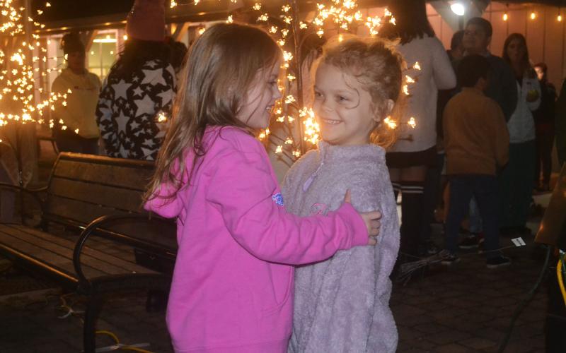 Henlee Jo Wilson and Karli Holcomb embrace one another in the spirit of Christmas at Demorest’s holiday event Wednesday night. BRIAN WELLMEIER/Staff