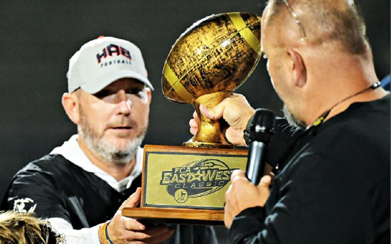 Habersham Central’s Benji Harrison gets his hands on the FCA East-West  Classic trophy after winning the game 23-0. ZACHARY TAYLOR/Special