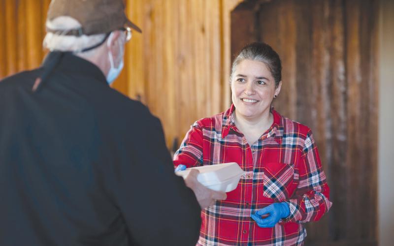 Doris Negron hands a meal to a guest at the community meal Thursday in Cornelia. TOM ASKEW/Special