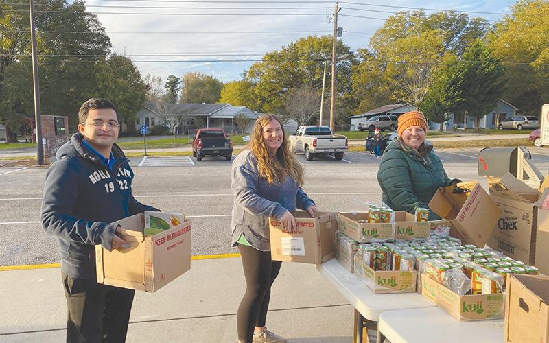 From left, Herber Morales, Kimberly Allen, Andrea Armour handle boxes of food for those in need.
