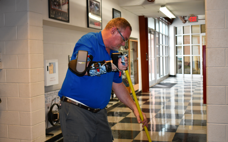 Carlton Lewis cleans the floor as he adapts to a new bionic arm brace. BRIAN WELLMEIER/Staff