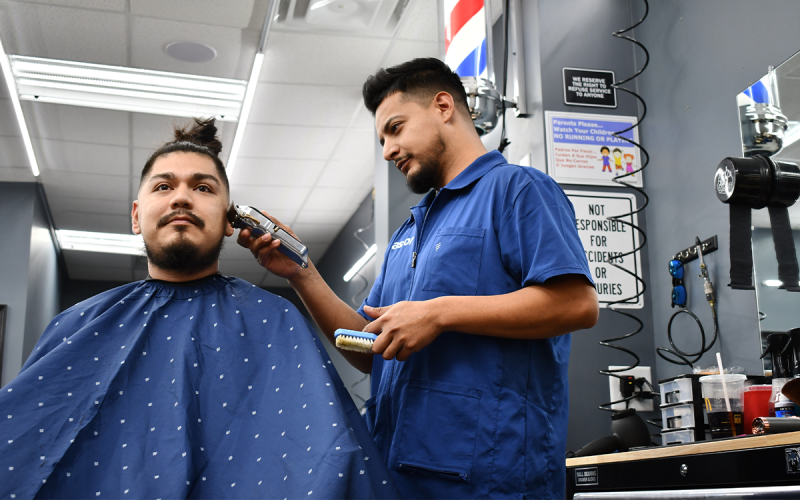 Barber Pastor Lara works on the hair of Miguel Ramirez. BRIAN WELLMEIER/Staff
