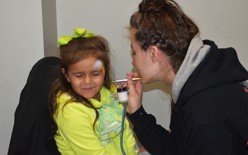 6-year-old Alexis Champlin, sits still while she gets her face airbrushed by Jada Holmes of Shadrix Living Art during the Easter Eggstravaganza at  Clarkesville’s First United  Methodist Church. AMARIS E. RODRIGUEZ/Staff