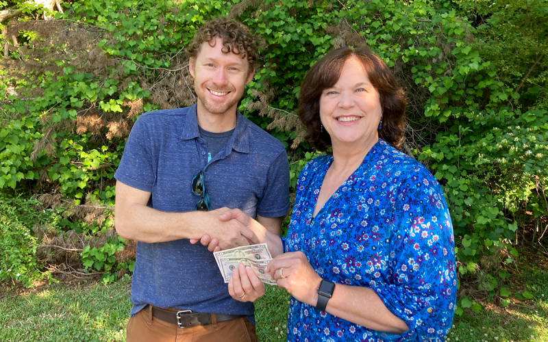 Dahlonega resident Rhonda Hardy receives her $100 prize money from The Dahlonega Nugget publisher Matt Aiken. Hardy’s photo of vintage Porsches traveling in the Northeast Georgia mountains will grace the cover of the 2022 summer edition of The Mountain Traveler magazine. CNI NEWS SERVICE