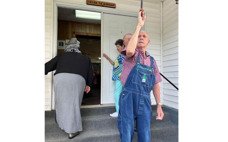 Deacon Benny Miller rings the bell discovered beneath the church in 1954, to begin the call to service Sunday. WAYNE KNUCKLES/CNI News Service