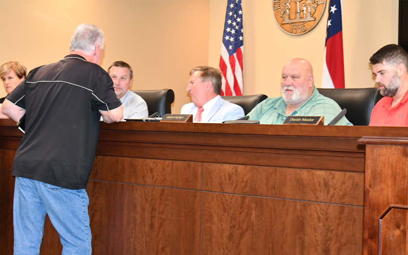 Larry Shedd of Clarkesville (back turned) consults with Commissioners Ty Akins and Bruce Harkness after Monday’s public hearing about the millage rate. MATTHEW OSBORNE/Staff
