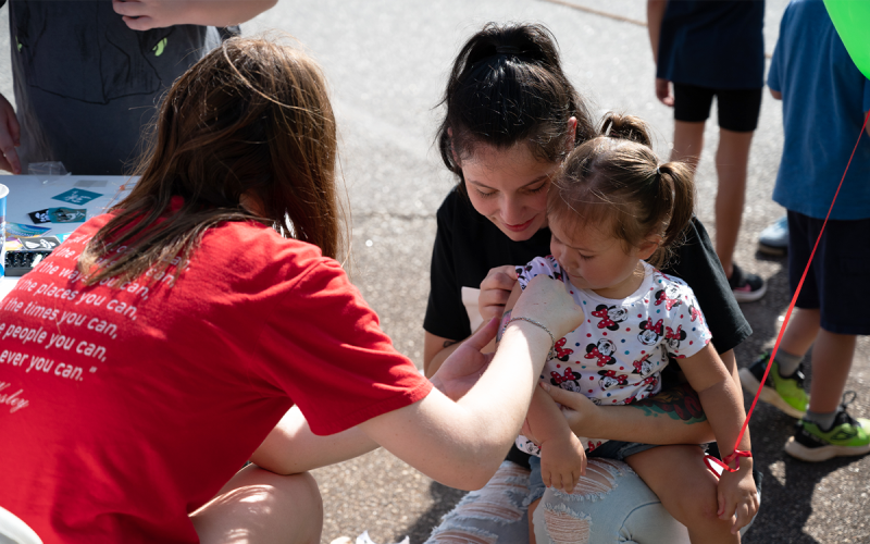 Cornelia United Methodist Church volunteer Addison Franklin paints a fairy on the arm of Lilly Toro-Jarrell while her mom holds up her sleeve. ZACH TAYLOR/Special