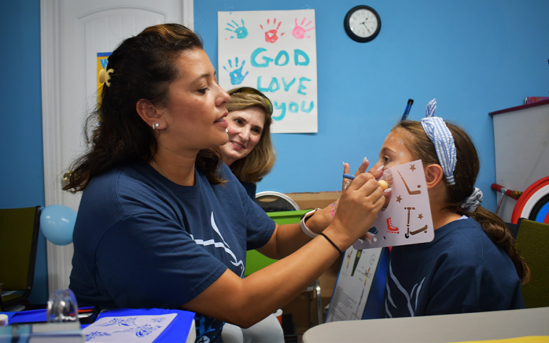 Melissa Miller applies sticker art on her daughter London Miller’s face at Saturday’s health fair. BRIAN WELLMEIER/Staff