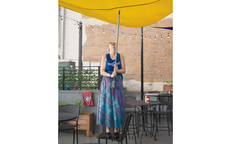 Fender’s owner Melissa Reeder, uses a broom handle to push rainwater out of the patio roofing at Saturday’s United Way kickoff concert event. Earlier in the day, there was fun for kids downtown at the splashpad, but the evening brought more water than anyone wanted. ZACH TAYLOR/Special