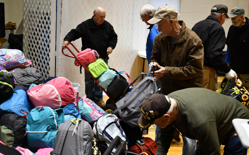 Volunteers (from left) Phil Watson, Tony Gray, Ranny Voight, Larry Lind and Ronnie Conrad help load up backpacks full of food, school supplies and toys for transport to children in need in West Virginia. MATTHEW OSBORNE/Staff