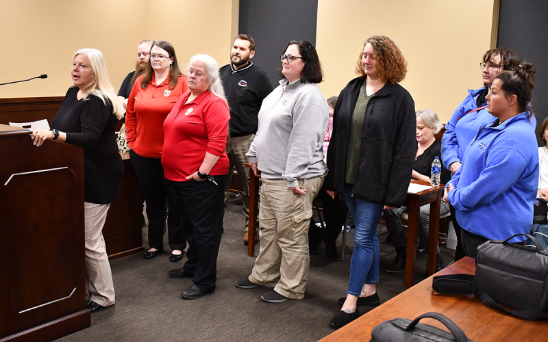 Standing in support of 911 Director Lynn Smith are (from left) Jaron Loggins, Belinda Konarski, Melanie Bellinger, Tom Priddy, Beth Alewine, Kailey Gould, Natalie Chuhran and Tangie Dean. MATTHEW OSBORNE/Staff
