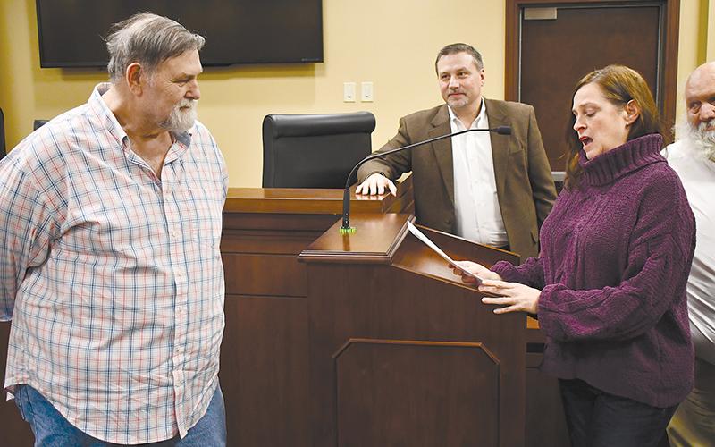 David Barrs (left) listens to a heartfelt speech by colleague Laurie Church at Monday’s county commission meeting as Commissioner Ty Akins looks on.