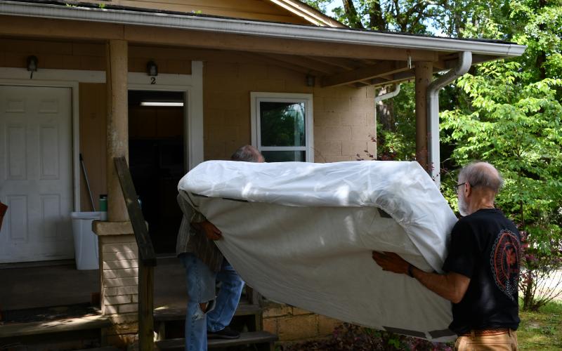 Brad White and Mike Miller bring a mattress inside the home beside Victory Baptist Church. Originally a larger house, the unit was split to accommodate two small families or two individuals. JOHN DILLS/Staff
