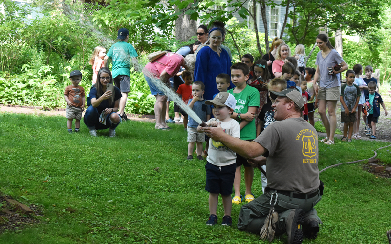 Children got an opportunity to pretend to fight of a forest fire, and Oliver Miles was a natural. Assistant Engine Captain with the U.S. Forest Service Thomas Black watched in awe. EMMA MARTI/Staff