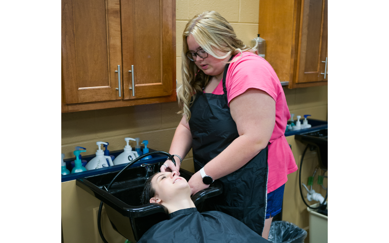 Addie Massaro (right) washes the shampoo out of Emily Irvin’s hair in a lab session. ZACH TAYLOR/Special