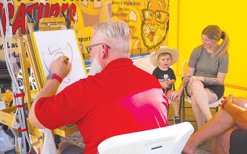 Graysen and Brandy Armour sit down for a caricature drawn by Jim Humphrey of Giggles and Grins Caricatures. ZACH TAYLOR/Special