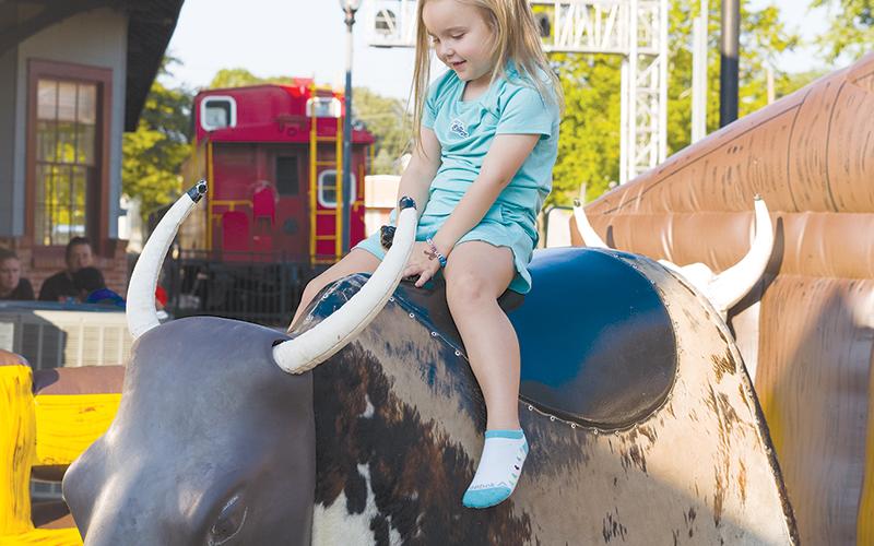 Ellie Miller rides the mechanical bull during the festival, which was the last of four such events held this summer. ZACH TAYLOR/Special