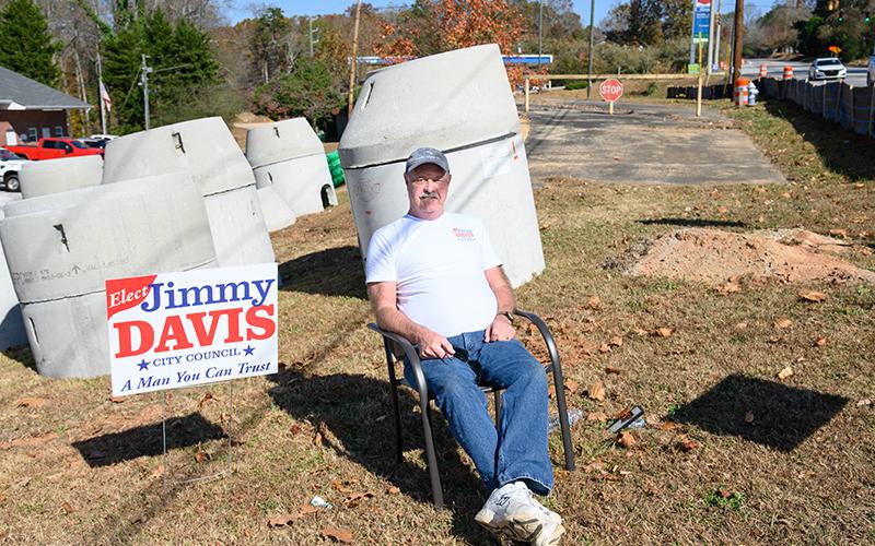 Jimmy L. Davis sits beside his signs near the voting precinct in Demorest as he campaigns for a city council seat. ZACH TAYLOR/Special