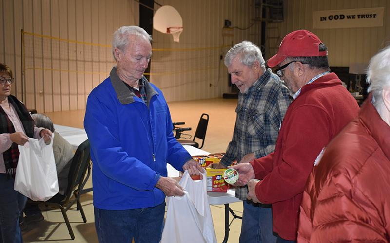Jim Miner walks through the line Friday for Habersham Food 2 Kids, getting items from Jerry Medlock and Jerre Harvard. MATTHEW OSBORNE/Staff