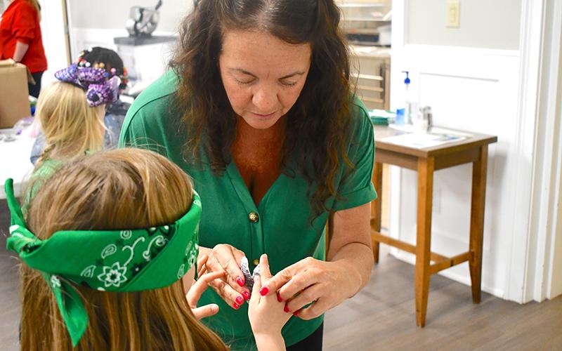 Girl Scouts leader Leigh Lipkin helps guide a scout in “pin the fly on the frog” in celebration of leap day. JULIANNE AKERS/Staff