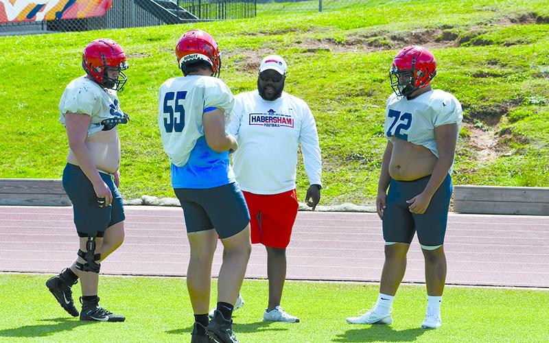 Coach Joe Powell lays out a drill for offensive linemen (from left) Noah McDowell, Braden Capazolli and Kris Hopkins. LANG STOREY/Staff