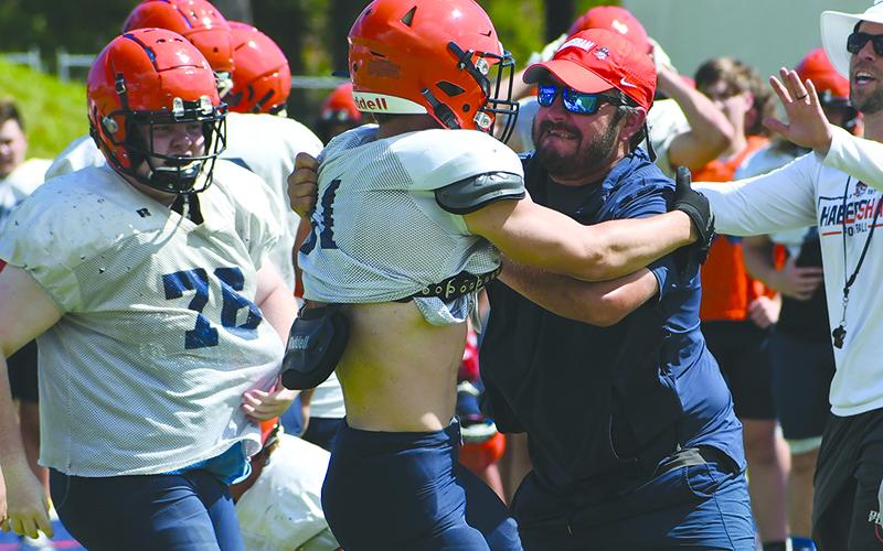 Coach Drew Ferguson pumps up Landyn Savage after Savage made a big play during live practice. LANG STOREY/Staff