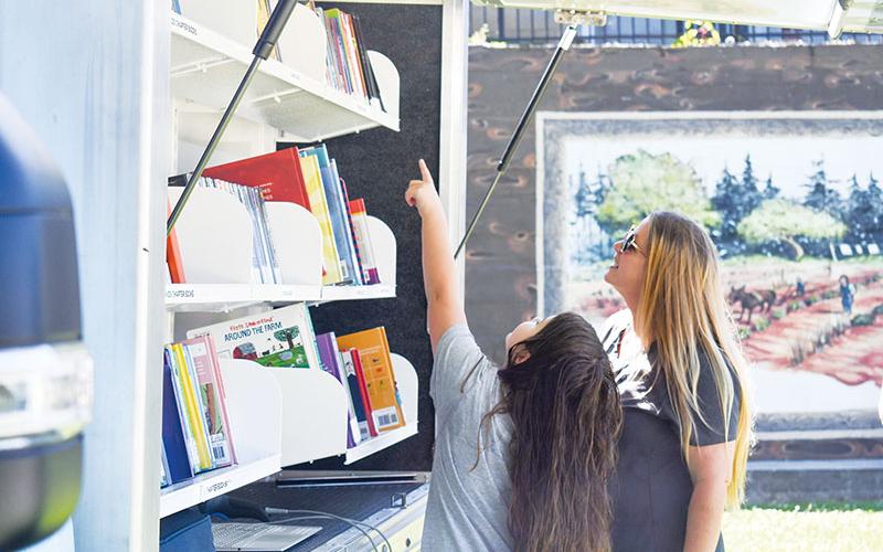 Brooklyn Houston, left, and her mother Amy Houston,  pick out a book from Piedmont  Regional Library System’s Pop up Rolling Library at the Baldwin Farmers’ Market on June 7.