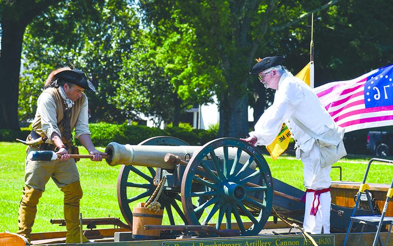 David Louden (left) and Ed Hendricks, dressed in Revolutionary War regalia, service a Revolutionary artillery cannon after it was set off at a Flag Day ceremony to honor Old Glory. JULIANNE AKERS/Staff