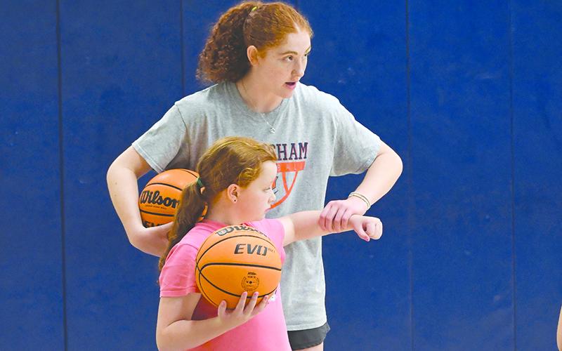 HCHS’ Daytona Underwood corrects the form of camper Gracie Hubbard at basketball camp this week. LANG STOREY/Staff
