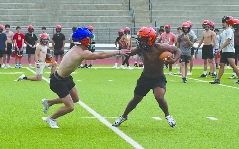 Teammates look on at Monday’s practice as ballcarrier Donnie Warren looks to shake off Landyn Savage. LANG STOREY/Staff