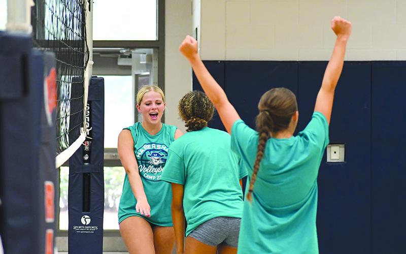 Ava Saxon (right) and McKenzie King hype up their teammate after Kinslee Hicks (far left) won a point during one of  Habersham Central’s summer camps. LANG STOREY/Staff