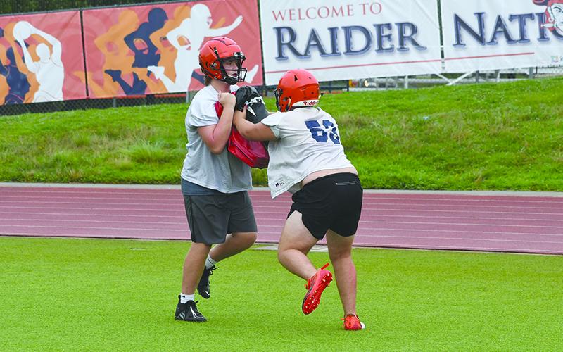Landon Holbrook holds the bag while Dawson Barnett blocks at practice Thursday morning. LANG STOREY/Staff
