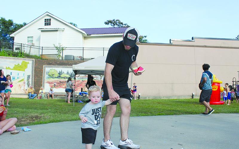 Devon Hoose helps his son, Weston Hoose, through the festivities toward the lawn Saturday at the Pit Nic in Baldwin. BRIAN WELLMEIER/Special
