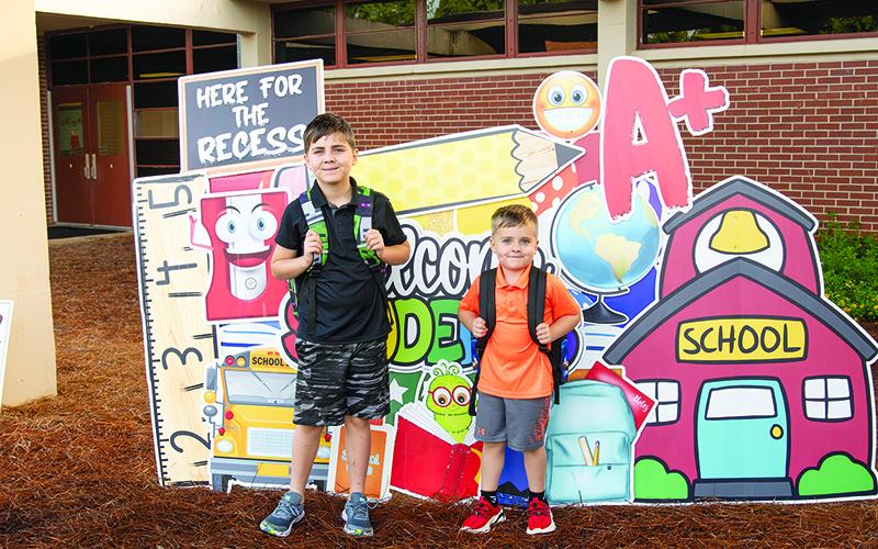 Lucas and Gunner Blankenship stand for a picture in front of the Drop The Card Yard Designs sign at Woodville Elementary School last Friday. ZACH TAYLOR/Special