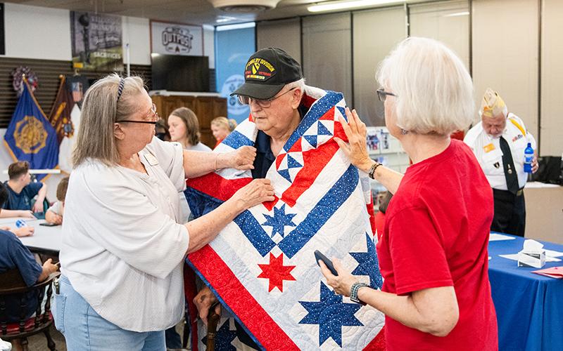 United States Army Veteran John Wikle gets his Quilt of Valor draped over his shoulders by Karen Trombley and Sharon Ruth. ZACH TAYLOR/Staff