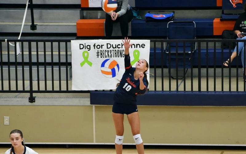 Ava Saxon serves during Habersham’s opening match of region play. In the background is a Dig for Duchanne sign made by students. LANG STOREY/Staff