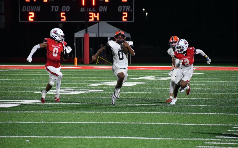 Donnie Warren splits a pair of Loganville defenders during the Raiders' 56-21 bashing of the Red Devils. LANG STOREY/Staff