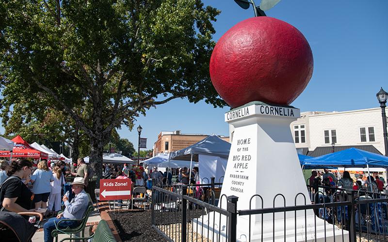 The Big Red Apple sits in the sun in downtown Cornelia on Saturday, surrounded by people. ZACH TAYLOR/Staff