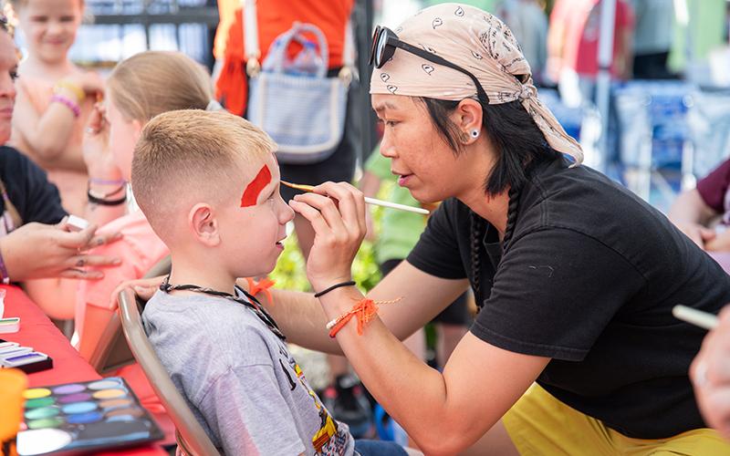 Holt Anderson gets his face painted by Lex Phommasouk at the Big Red Apple Festival on Saturday.
