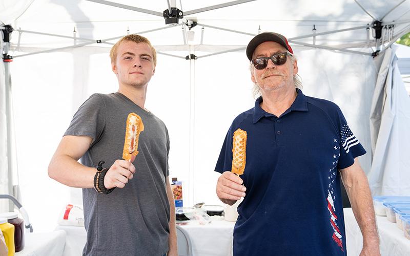 Matthew Shelton and Russ Borner hold up waffles and waffle dogs on a stick. The duo has been in business for a while, honing their waffle-making skills at festivals. ZACH TAYLOR/Staff