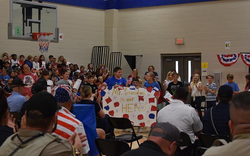 Students hold a banner celebrating Fairview’s own hometown hero Brandon Thompson, a paraprofessional. From left to right holding the banner is Landon Eller, Sylias McClure, and Addison Allen. JULIANNE AKERS/Staff
