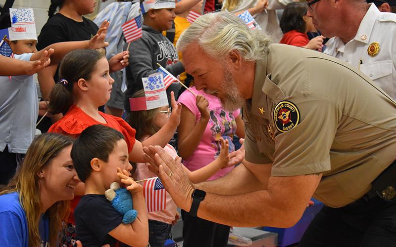 Habersham County Sheriff Joey Terrell gives Fairview student Ethan Coker a big high-five with teacher Carleen Monti behind him cheering him on. JULIANNE AKERS/Staff